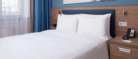 Une chambre d’hôtel avec un lit, une table de chevet avec un téléphone et un tableau au mur.