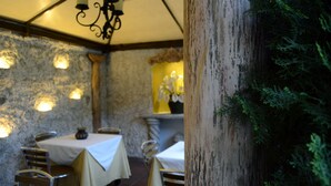 A restaurant with stone walls, tables with white tablecloths, and hanging lights. - Hostal Villa Toscana (Guatemala City)