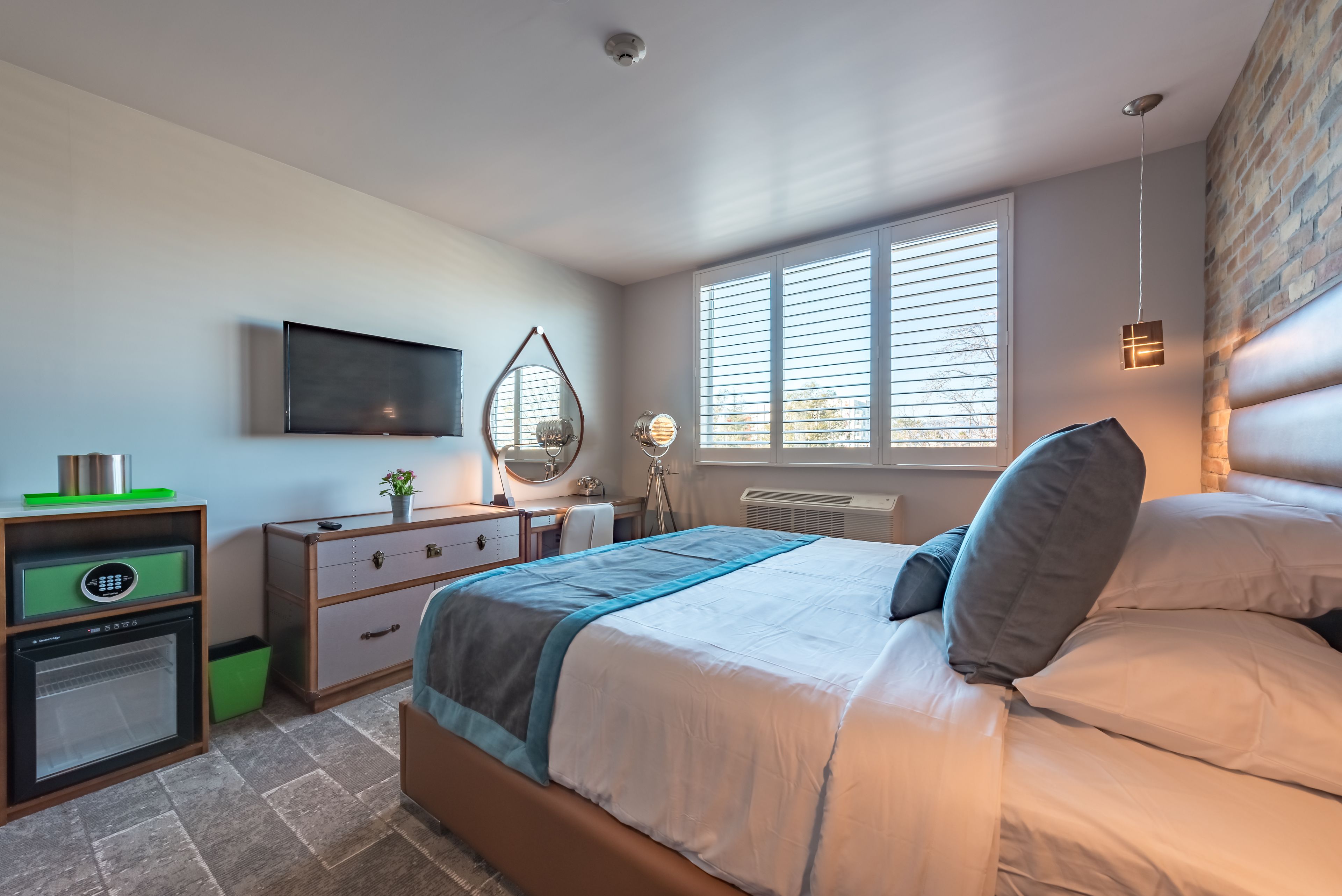 Una camera da letto con un letto, una cassettiera, una toeletta e un televisore appeso al muro.