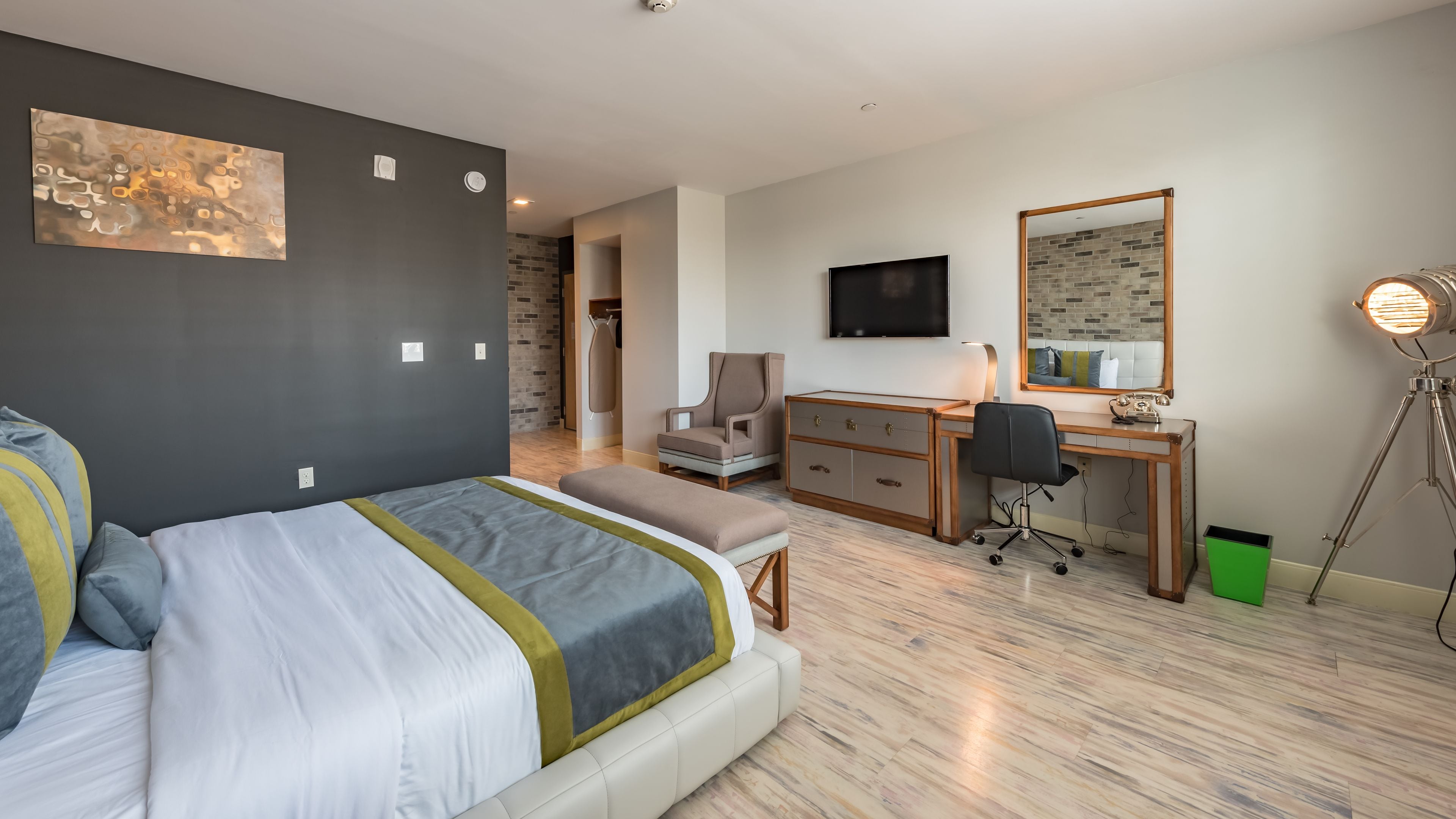 Una habitación de hotel moderna con una cama, un escritorio, una silla, un televisor y un espejo.