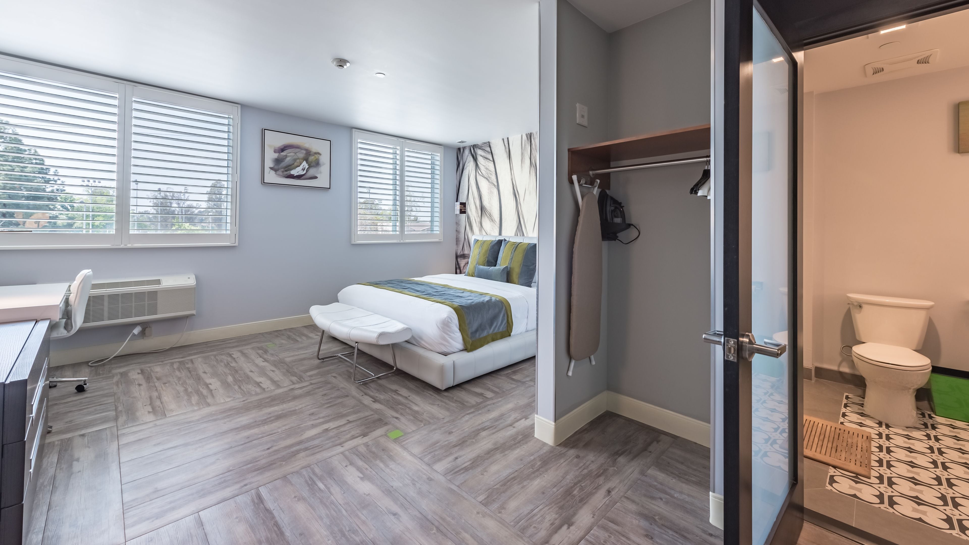 Ein modernes Schlafzimmer mit Bett, Nachttisch und Blick ins Freie durch große Fenster.