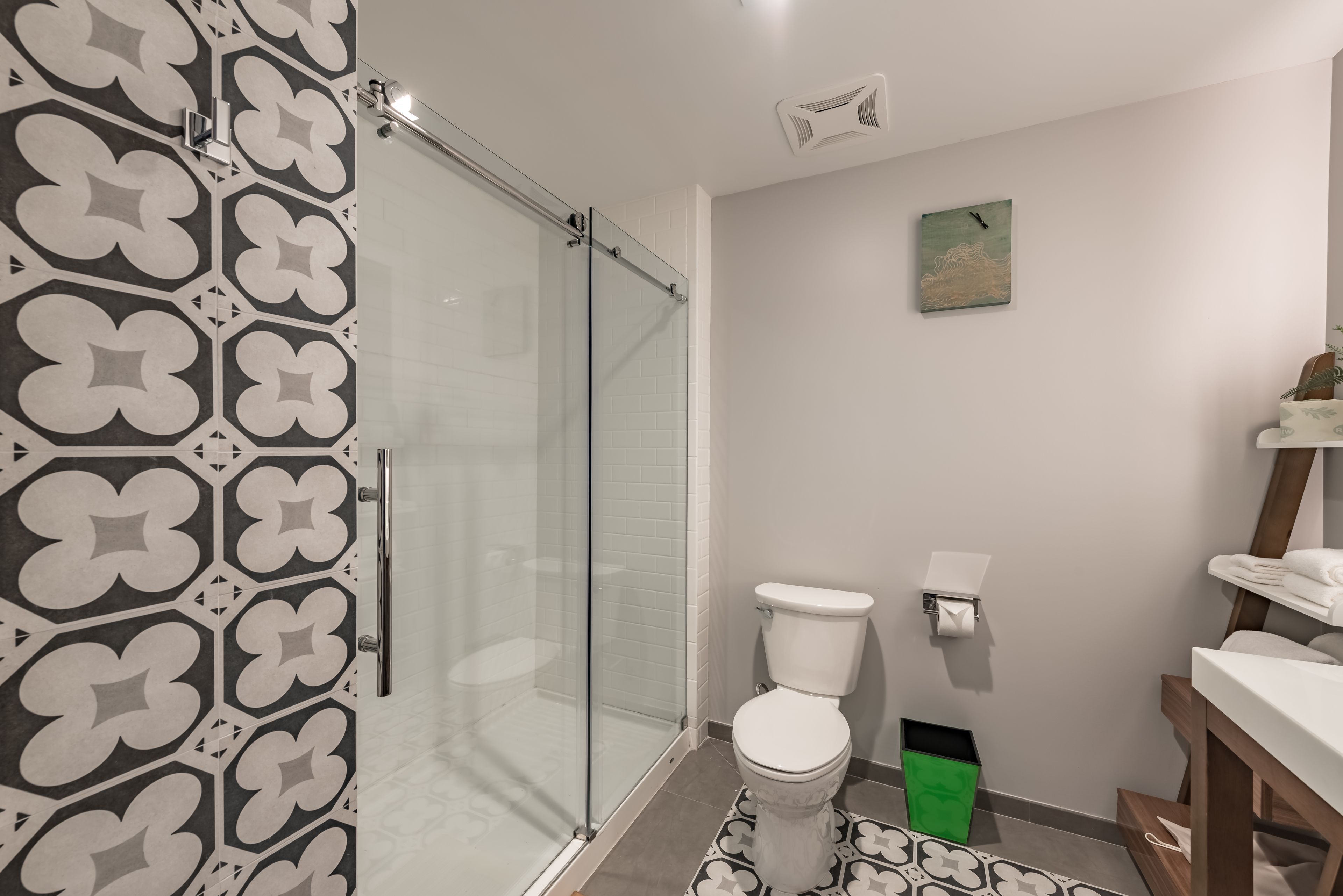 A modern bathroom with a glass shower enclosure, a white toilet, and a patterned floor.