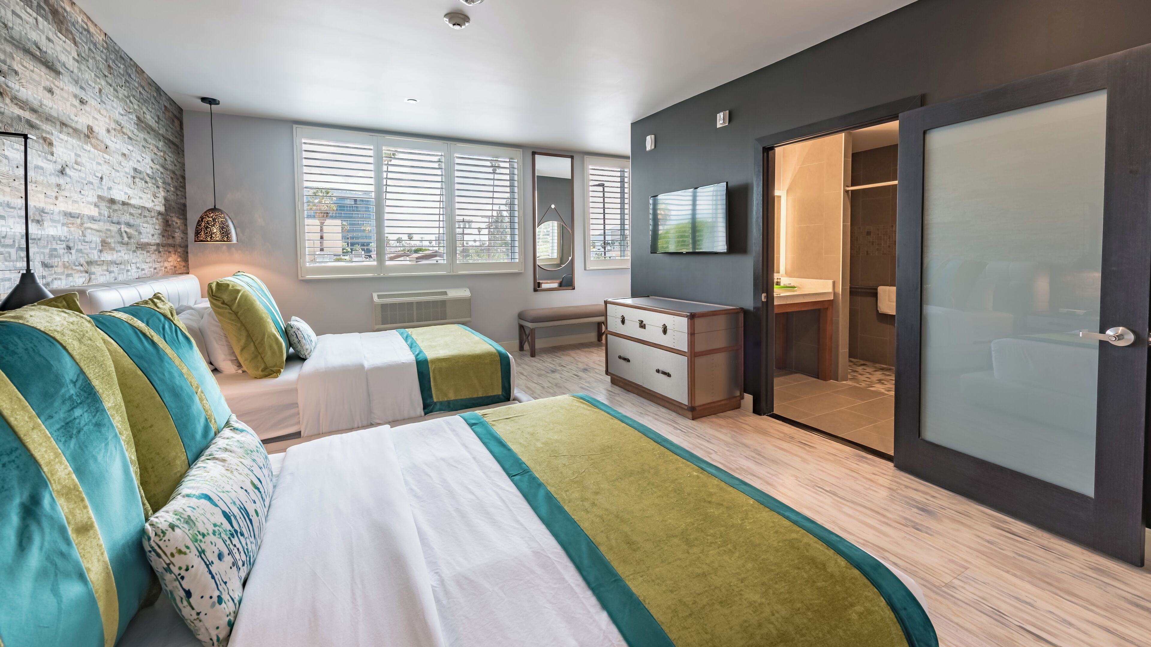 Une chambre moderne avec deux lits, une commode, un banc et un téléviseur.