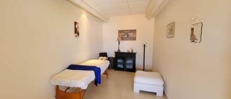 A small, clean room with two single beds, a small table, and a cabinet.