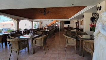 An indoor dining area with wicker furniture, a statue, and a staircase leading to an upper level.