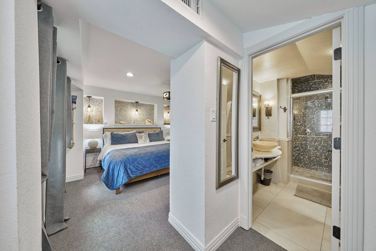 A bedroom with a bed, bedside tables, and a large mirror.