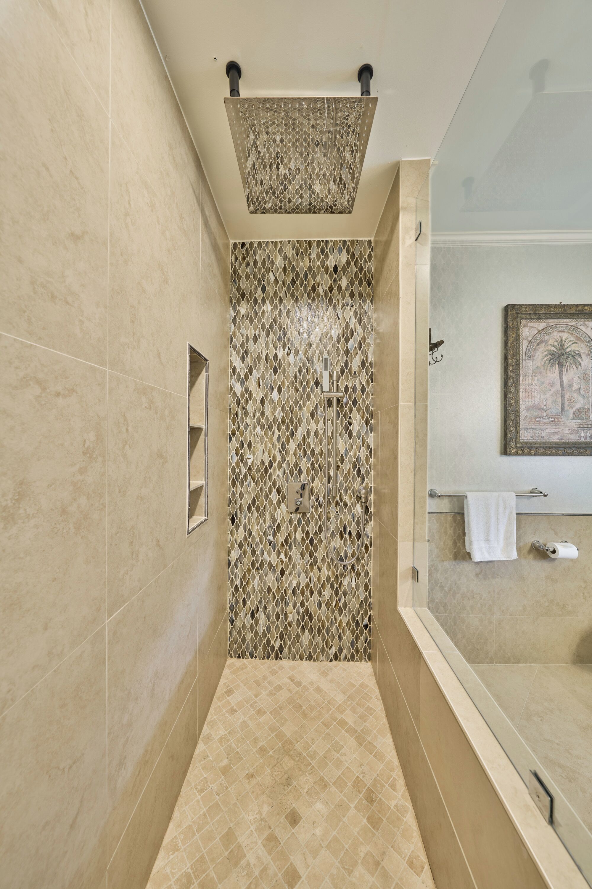 Une salle de bain moderne avec une douche, des murs carrelés, un tableau encadré et un porte-serviettes.