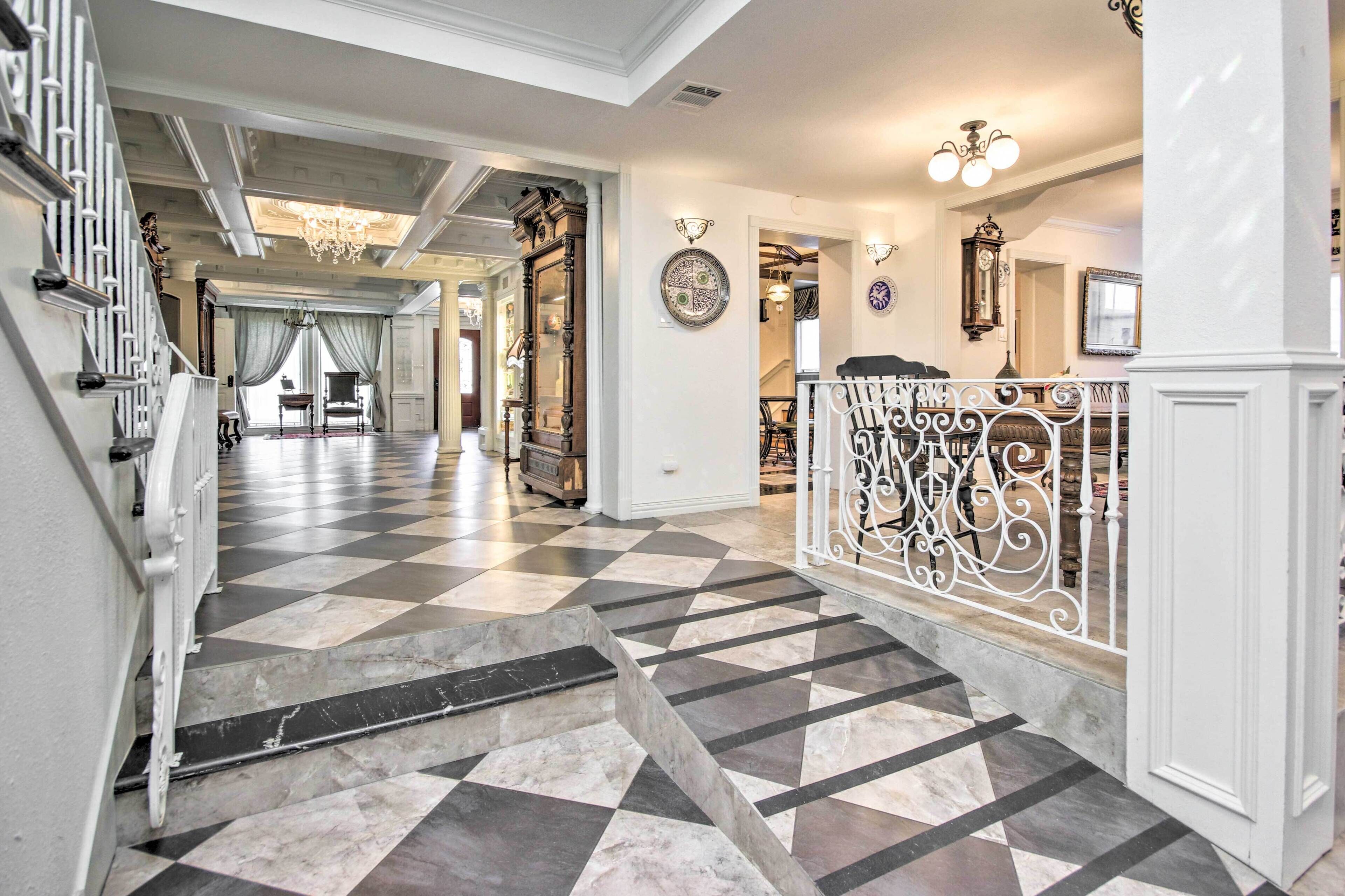 A grand hallway with a checkered floor, ornate railings, and a chandelier.
