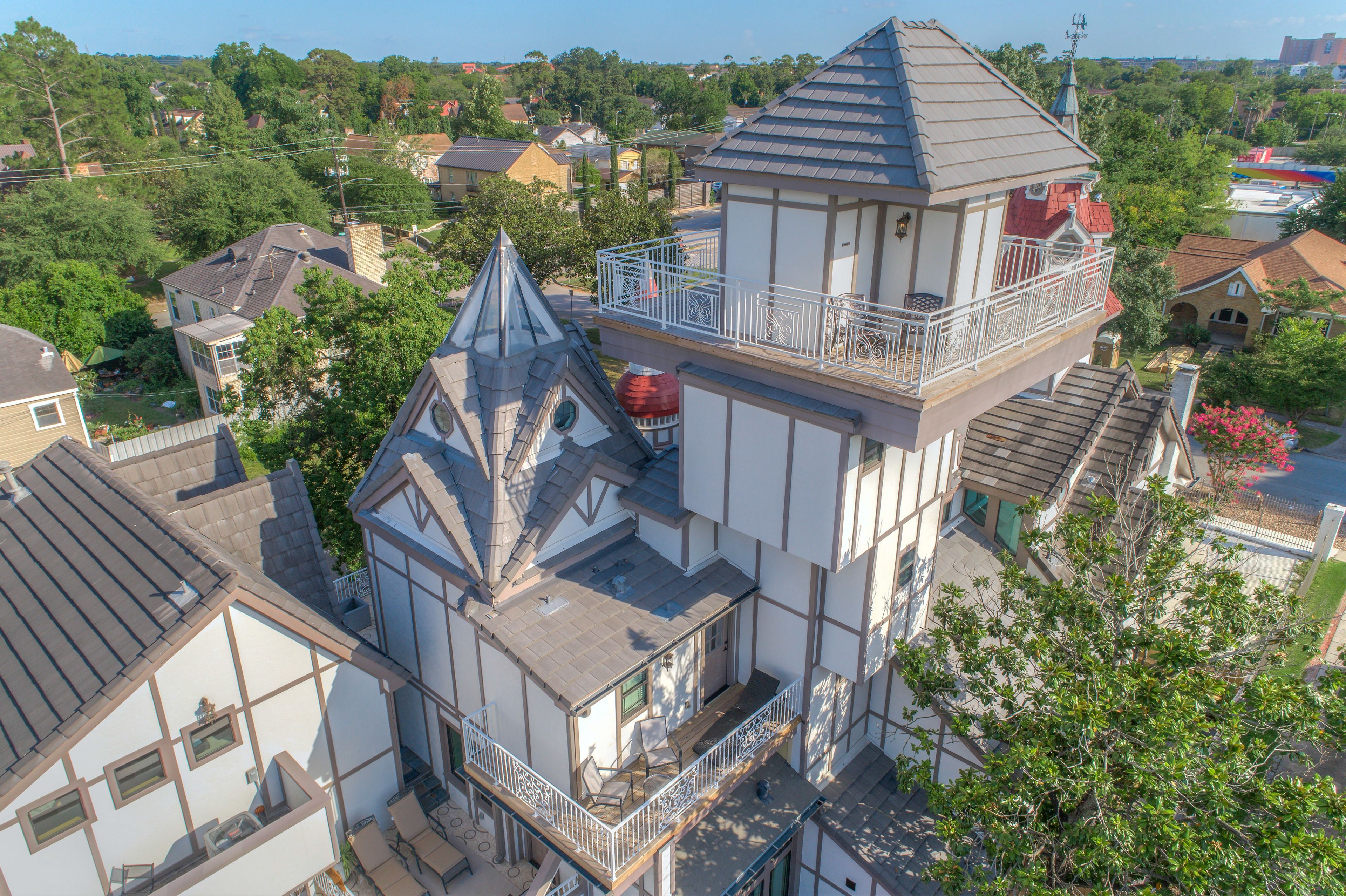 Ein mehrstöckiges Gebäude mit einem markanten Turm, Balkonen und einer Mischung aus Wohn- und Geschäftshäusern im Hintergrund.