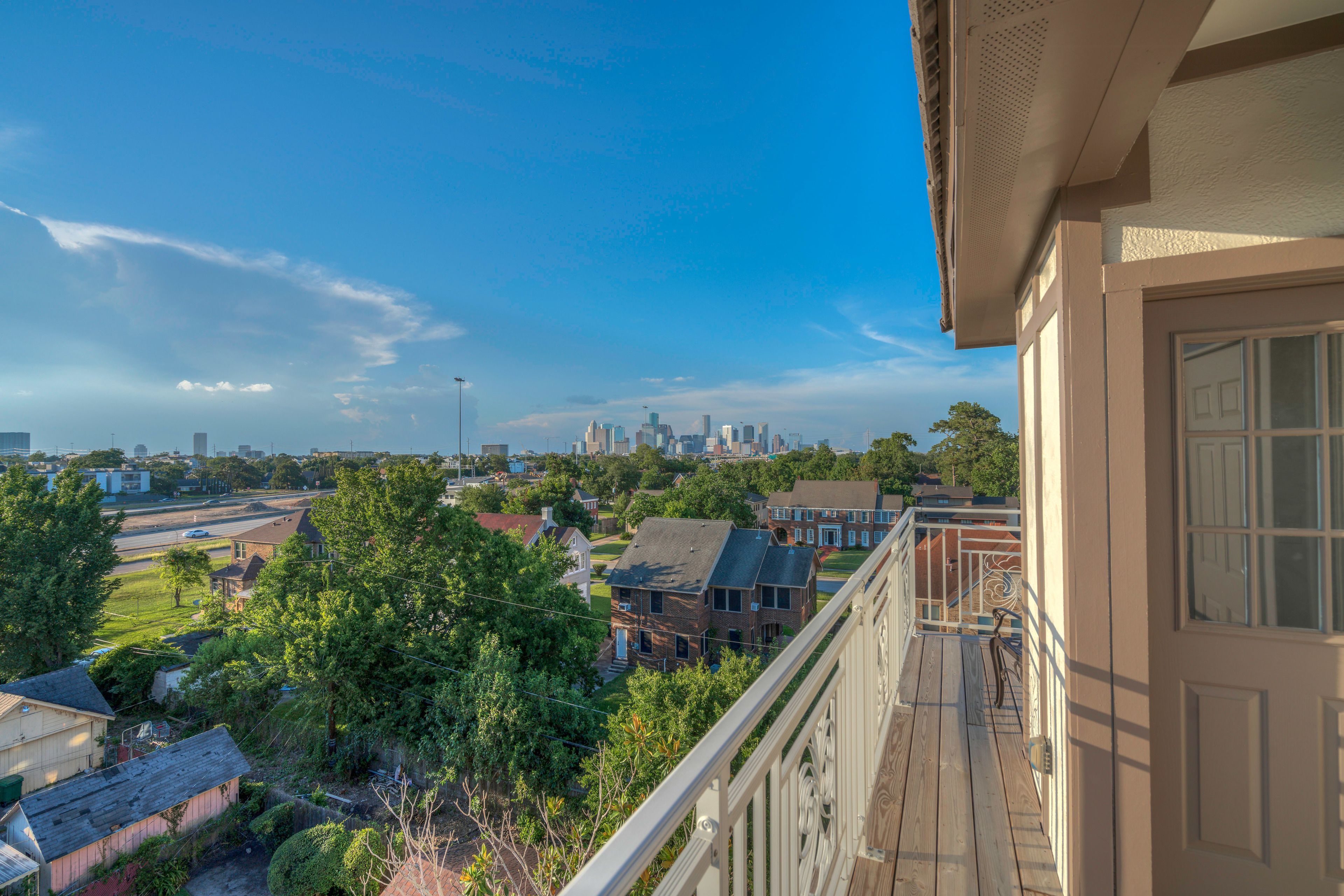 Un balcon offrant une vue sur les gratte-ciel de la ville, les immeubles résidentiels et un parc verdoyant.