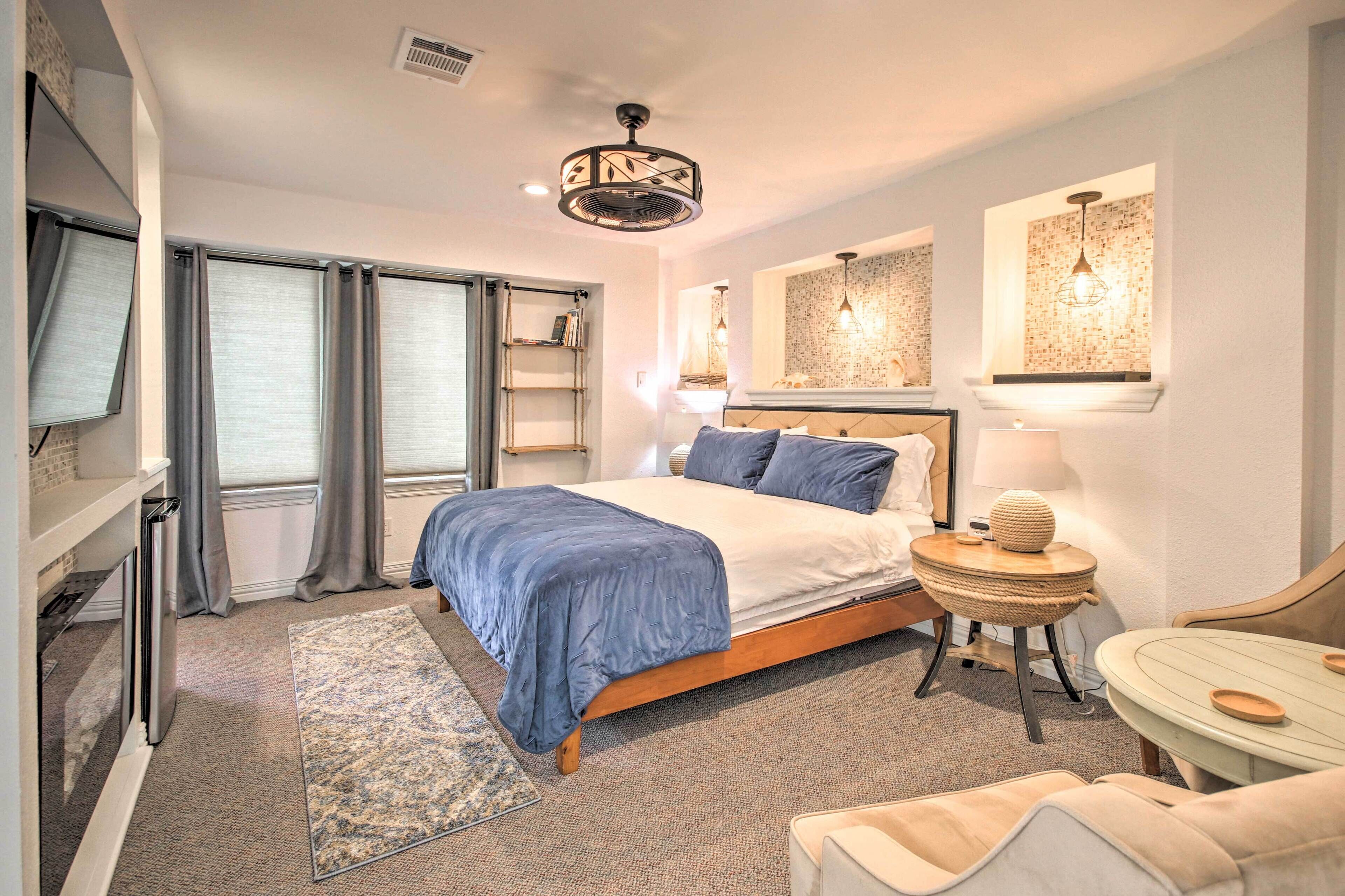 A modern bedroom with a large bed, a bedside table, a lamp, and a small round table with a decorative item.