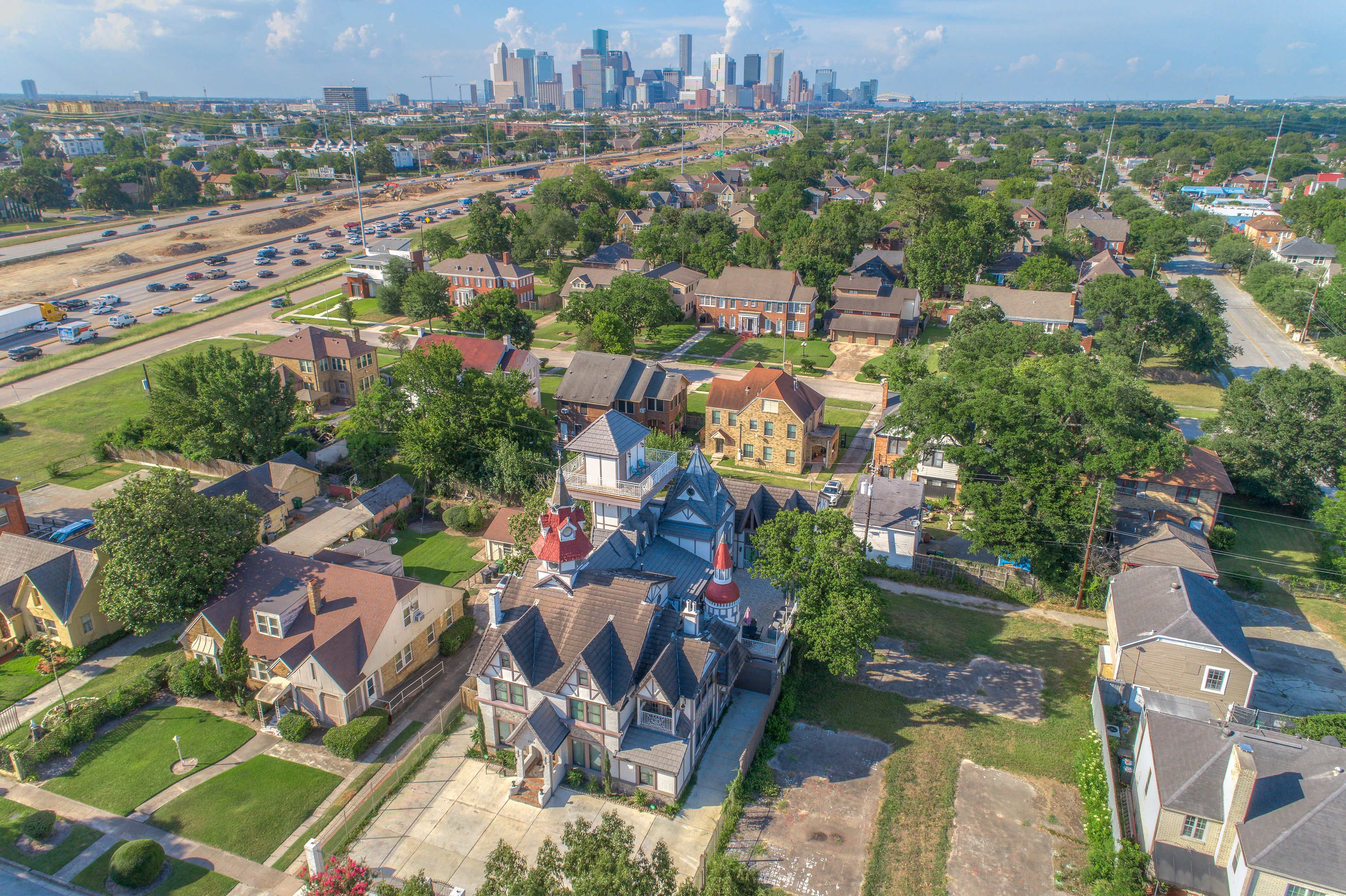 Vista aérea de una zona residencial con casas, calles y un horizonte de ciudad distante.
