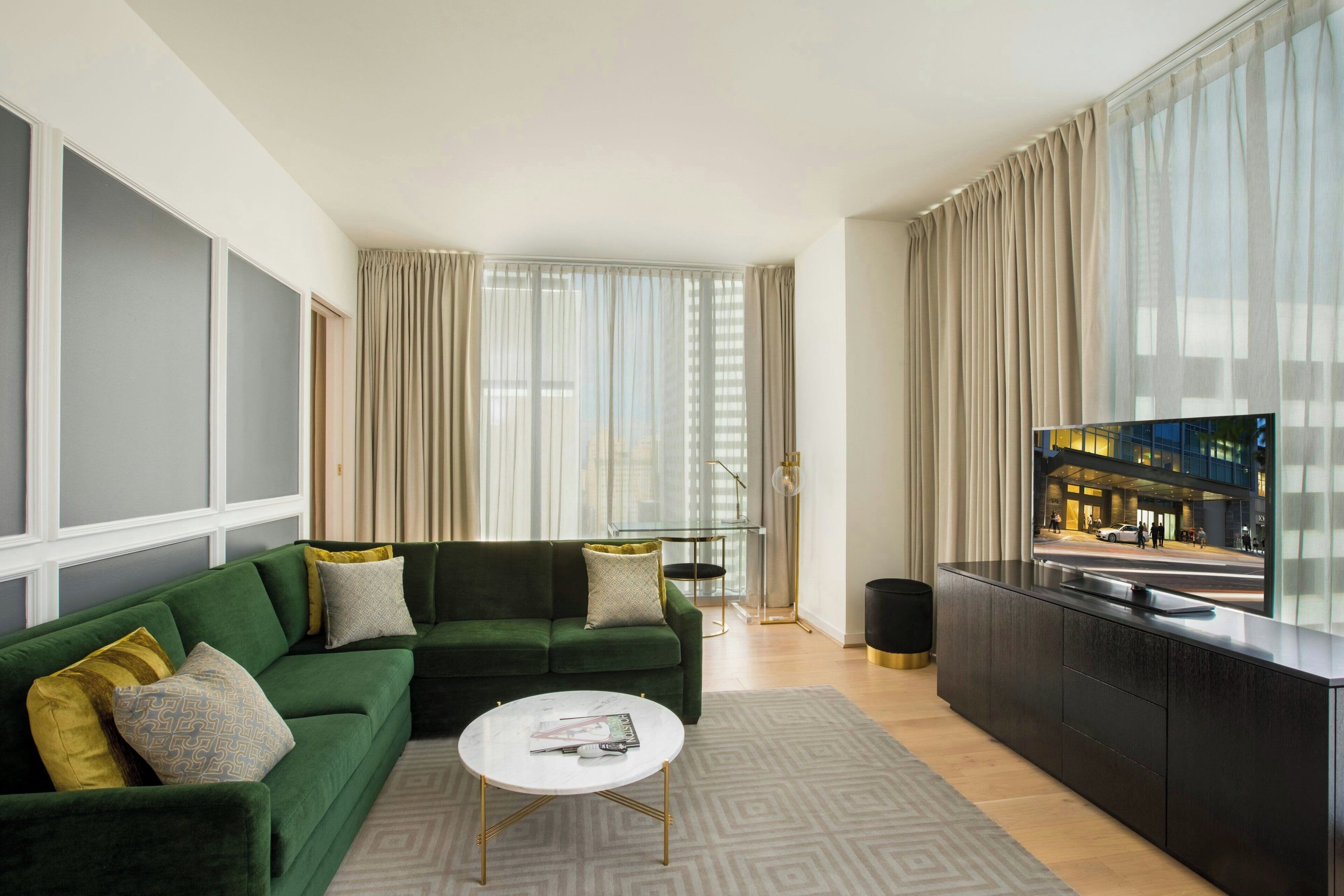 A modern living room with a green sofa, a white coffee table, and a large flat-screen TV.