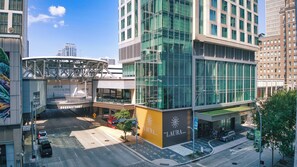 A modern hotel with a glass facade, a rooftop terrace, and a sign for 'The Laura Hotel'.