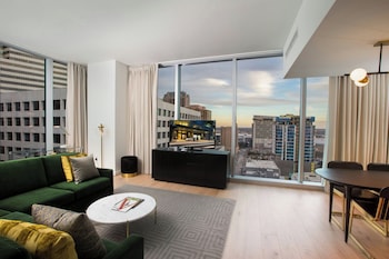 Enjoy a panoramic city view from the comfort of this stylish room, featuring a sofa, coffee table, dining area, and flat-screen TV. at The Laura Hotel, Houston Downtown, Autograph Collection