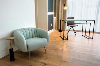 Relax in a stylish room with a comfortable armchair, side table, and glass-top table. at The Laura Hotel, Houston Downtown, Autograph Collection