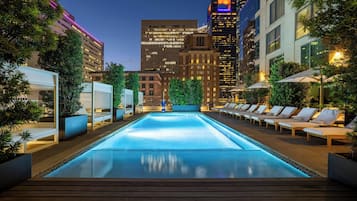 Una piscina al aire libre, camas de piscina con cargo, sombrillas