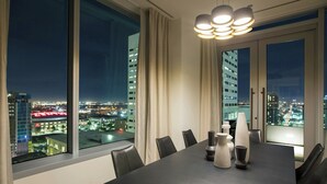 A modern conference room with a large table, chairs, and a city view through large windows.