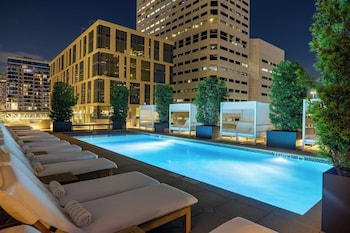 Relax by the pool surrounded by comfortable lounge chairs and lush greenery. at The Laura Hotel, Houston Downtown, Autograph Collection