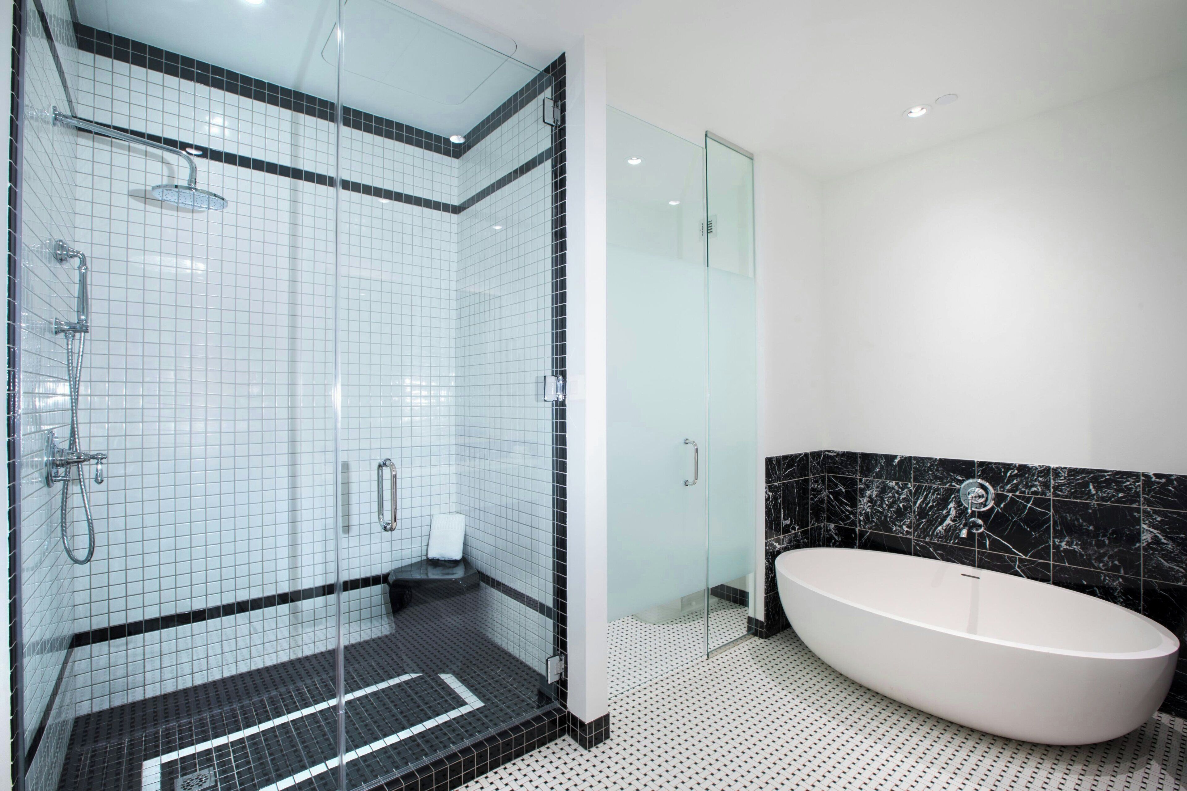 Un baño moderno con ducha de vidrio, una bañera independiente y piso de baldosas.
