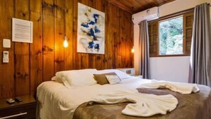 A wooden-paneled room with a bed, a painting, and a window with curtains. - Villa Vintage Campos (Campos do Jordão)