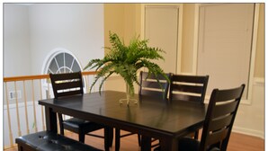 A dining area with a dark wooden table, four chairs, a bench, and a potted plant. - Opis Realty-Spacious Metro Atlanta Home (Conyers)