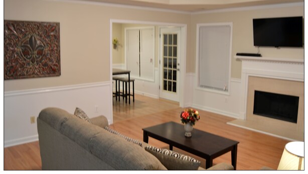 A living room with a sofa, a coffee table, a fireplace, and a television mounted on the wall. - Opis Realty-Spacious Metro Atlanta Home (Conyers)
