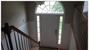 A staircase with wooden balusters leading to a white door with a glass panel above it. - Opis Realty-Spacious Metro Atlanta Home (Conyers)