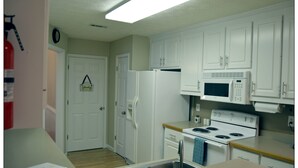 A kitchen with white cabinets, a microwave, a stove, and a sink. - Opis Realty-Spacious Metro Atlanta Home (Conyers)