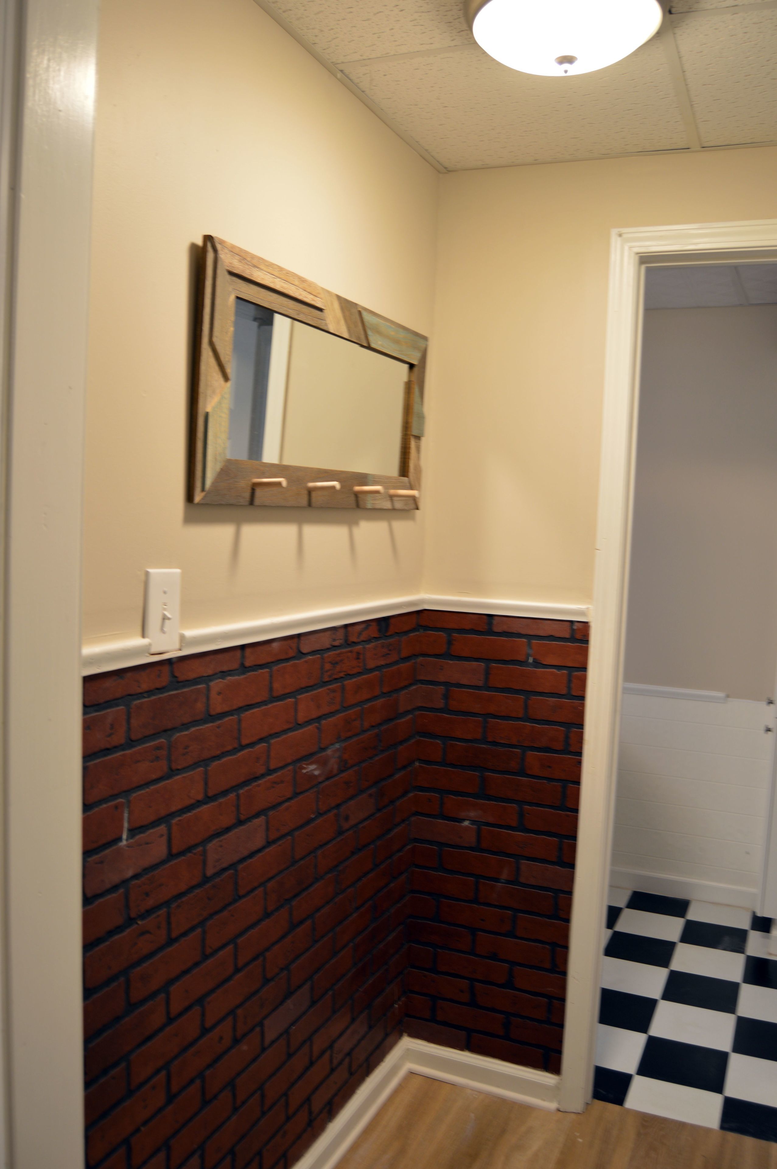 A corner with a brick wall, a white door, and a black and white checkered floor.