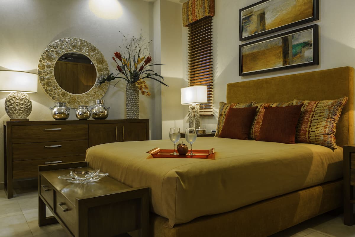 Un dormitorio ordenado con una cama grande, mesitas de noche, un tocador y un espejo.