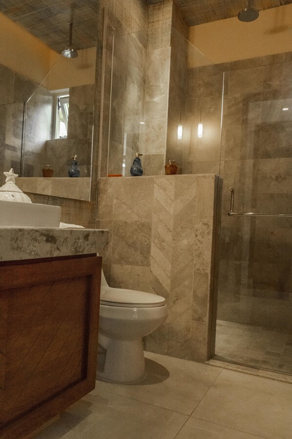 Une salle de bain avec un lavabo en marbre, des toilettes et une douche à parois de verre.