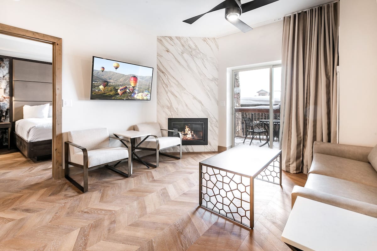 Una sala de estar moderna con chimenea, un sofá, una mesita de centro y un televisor montado en la pared.