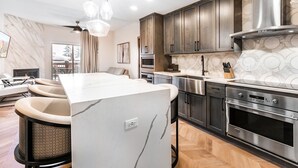 A modern kitchen with a central island, stainless steel appliances, and a herringbone wood floor. - Canyons Village Condos by All Seasons Resort Lodging (Park City)