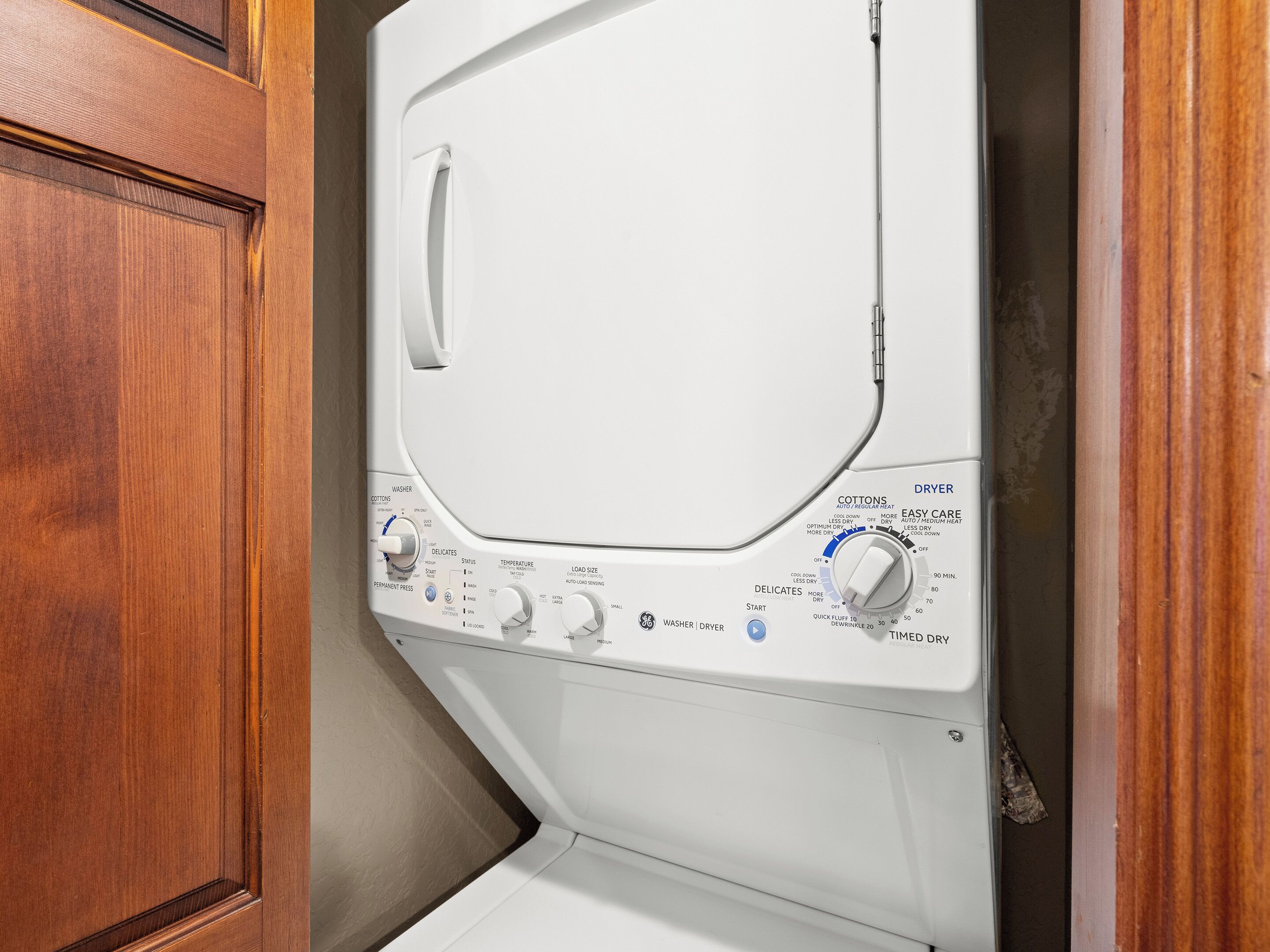 Vue de face d’un lave-linge, avec ses boutons de commande et ses étiquettes indiquant les différents programmes de lavage.