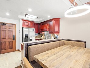 Eine Küche mit Holzausbau, einem Edelstahlkühlschrank, einem eingebauten Backofen und einem Holzessttisch mit einer Bank.