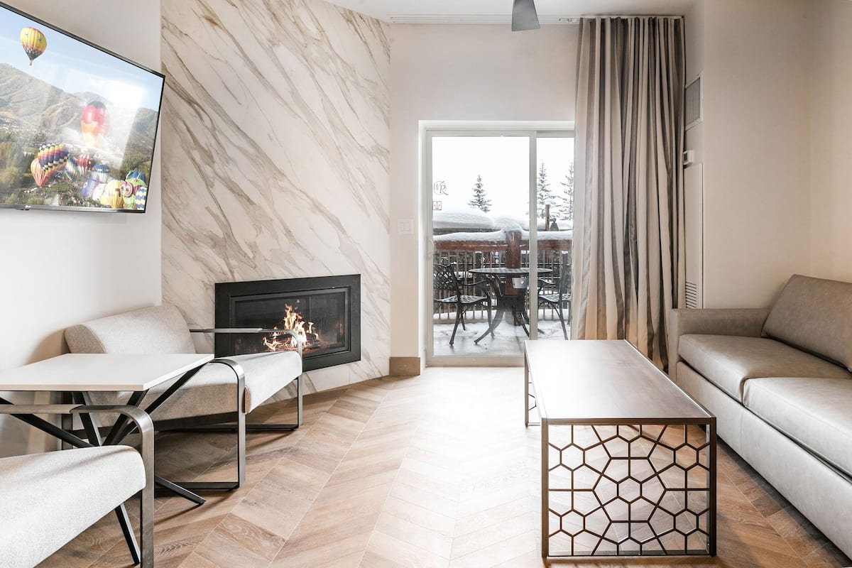 Una sala de estar moderna con chimenea, un sofá, una mesa de centro y un televisor que muestra globos aerostáticos.