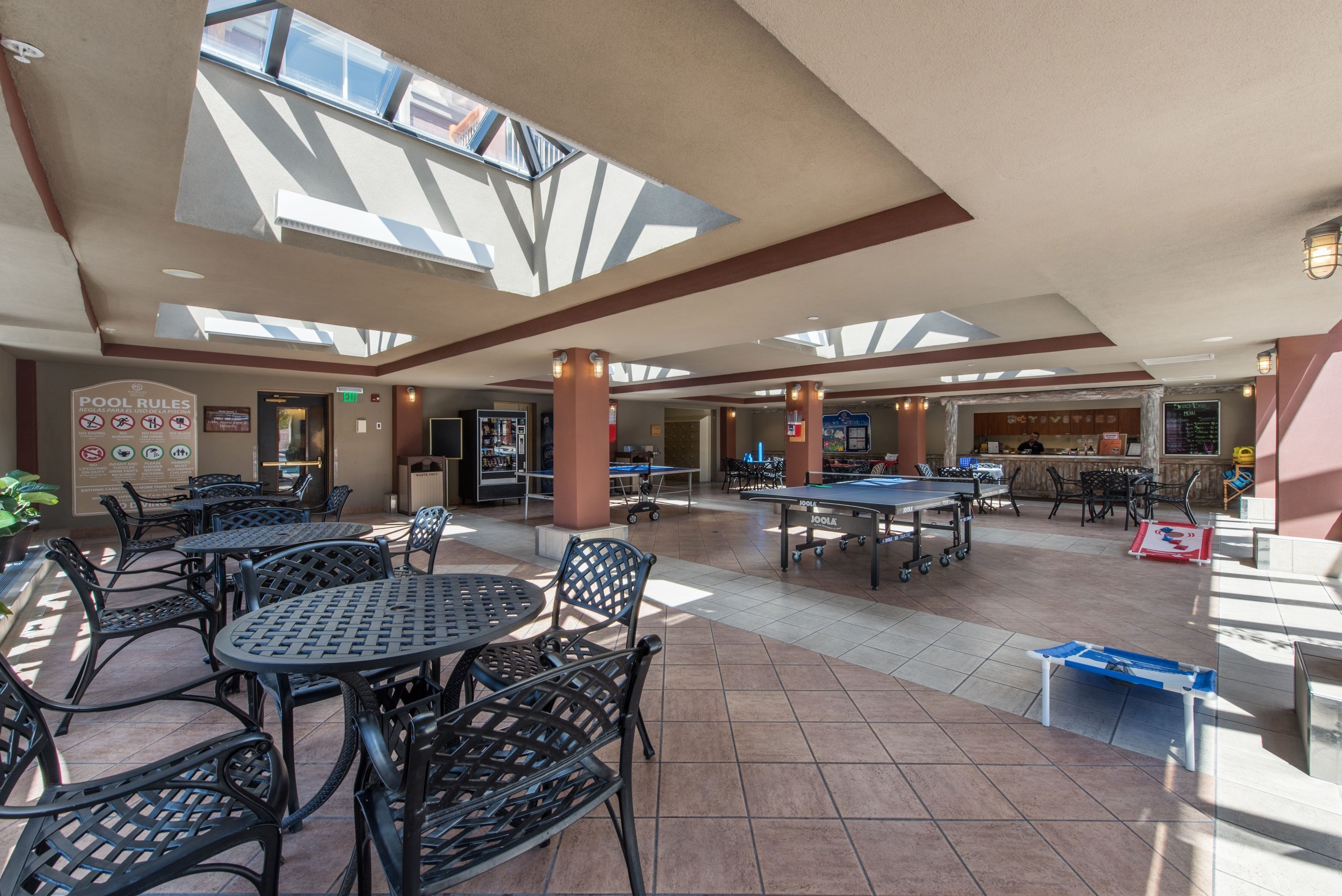 A spacious indoor area with multiple tables and chairs, a pool table, and a billiards table.