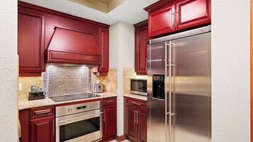A kitchen with red cabinets, stainless steel appliances, a microwave, and a built-in oven.
