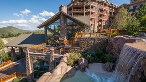 A hotel with a large waterfall, stone architecture, and multiple balconies. - Canyons Village Condos by All Seasons Resort Lodging (Park City)