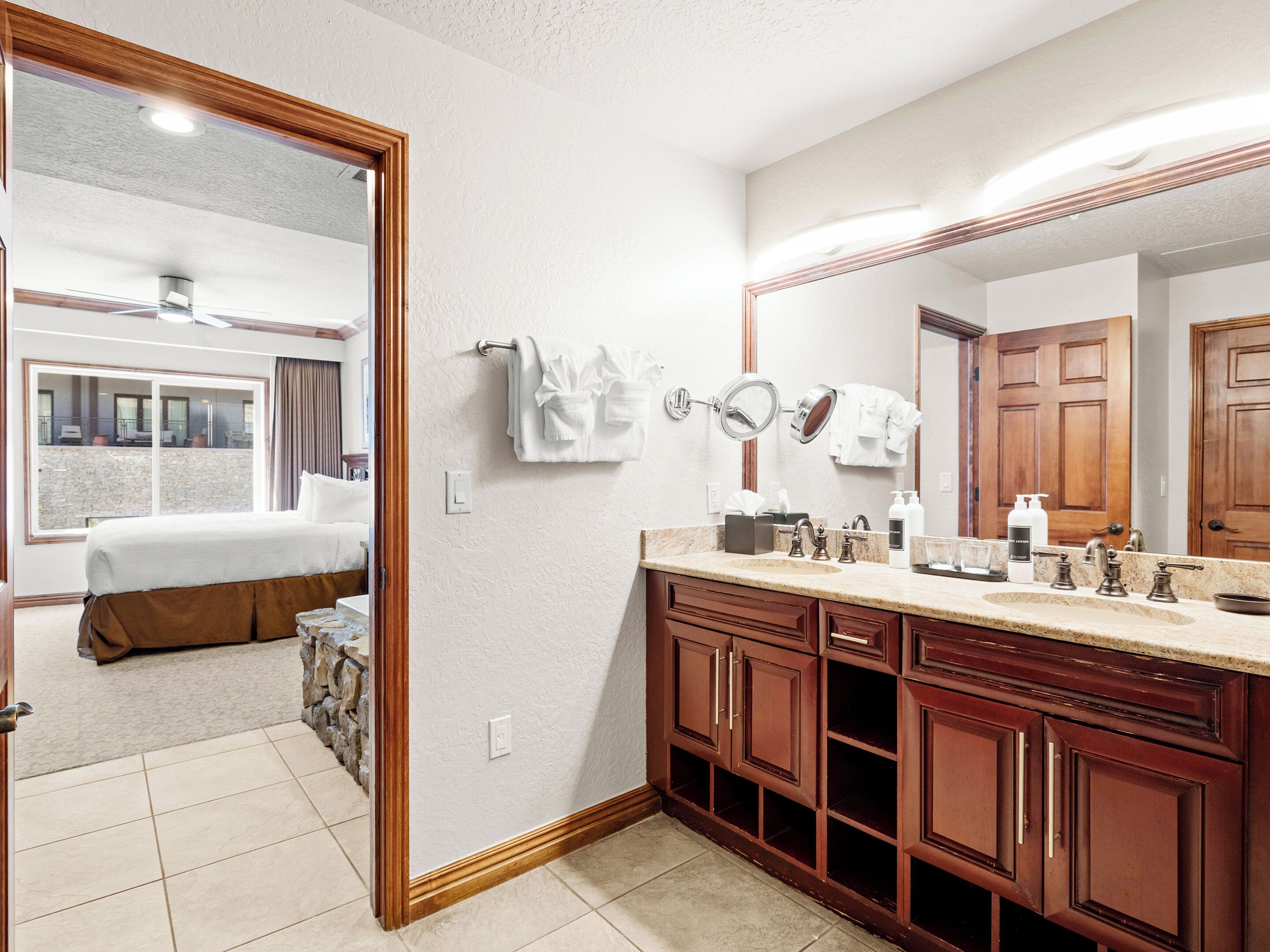 Um banheiro de hotel com um espelho grande, armários de madeira, uma pia e um porta-toalhas.
