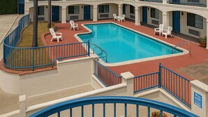 Un hotel con piscina central, varios balcones y zonas de estar al aire libre.