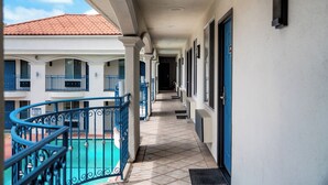 Un corredor cubierto con piscina, balcones y suelo de baldosas.