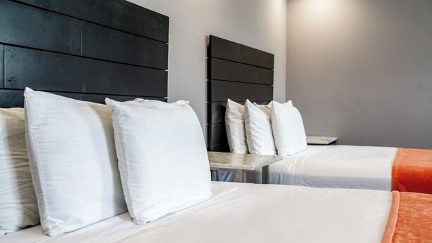 Habitación de hotel con dos camas, cada una con ropa blanca y almohadas.