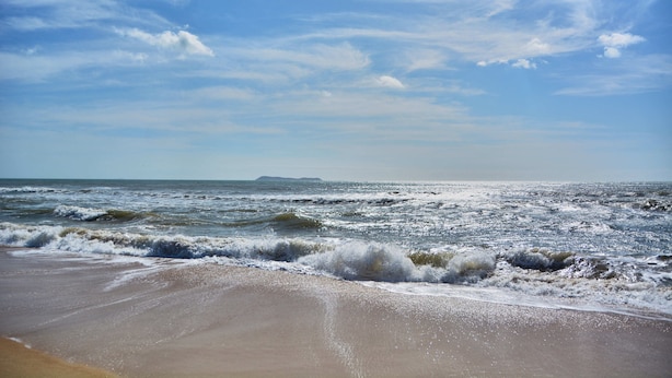 Uma praia com ondas e céu claro.