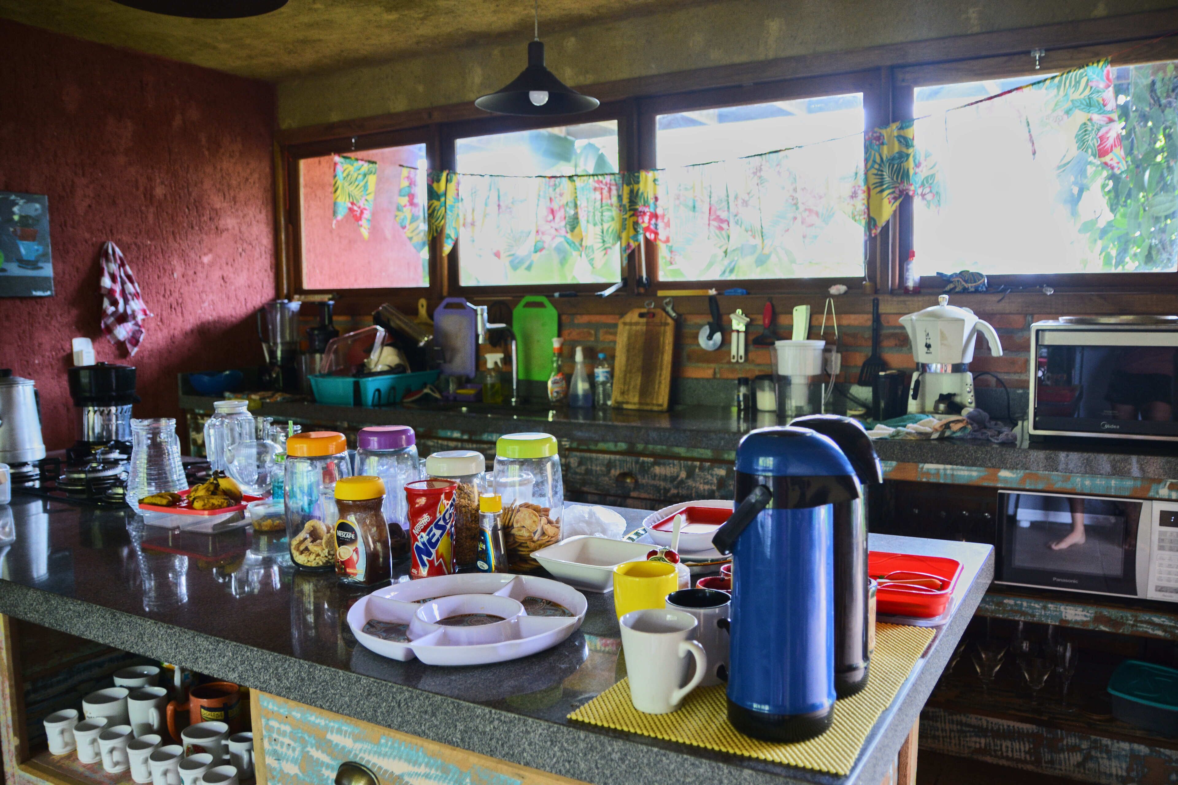 Una cocina con encimera de granito, diversos electrodomésticos y una ventana con vistas a la vegetación.