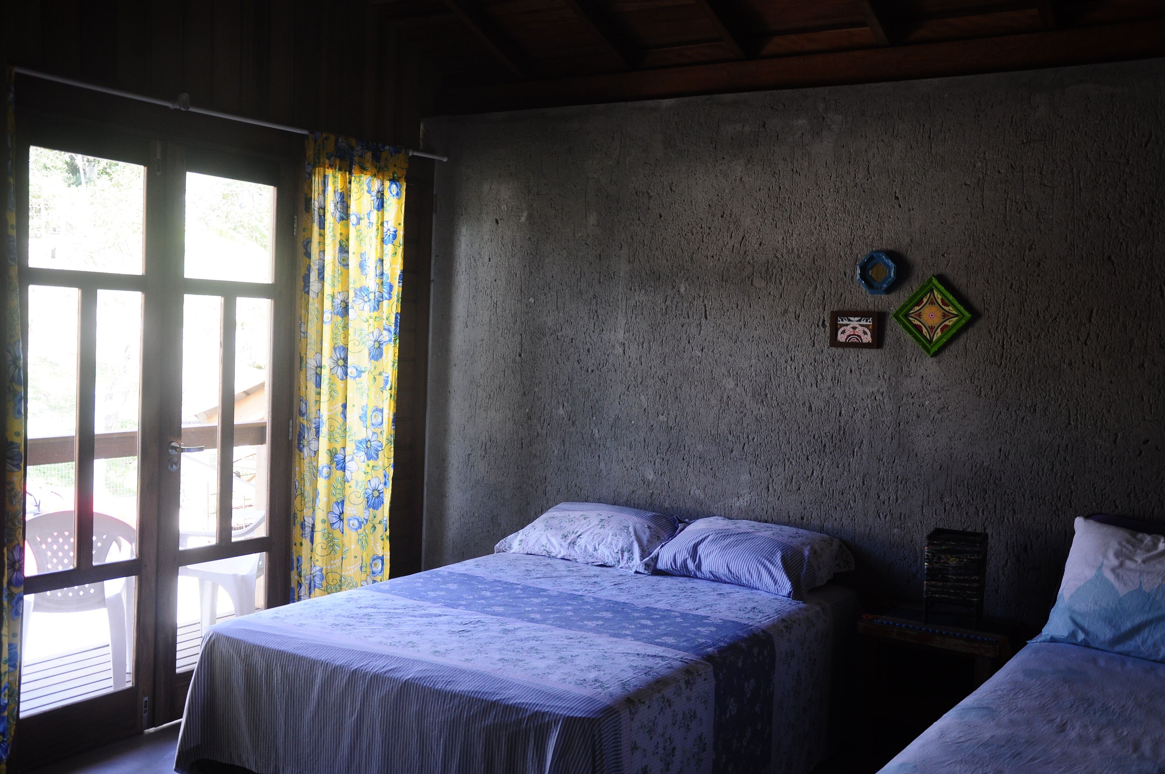 A bedroom with a bed, a nightstand, and a window with curtains.
