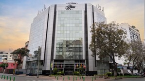 Un hôtel moderne doté d’une façade en verre remarquable, d’une entrée centrale et de plusieurs drapeaux exposés à l’extérieur.