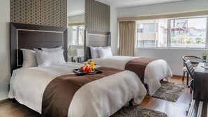 Une chambre d’hôtel avec deux lits, un coin repas et une vue sur la ville.