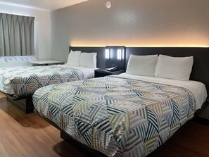 A hotel room with two beds, each with patterned bedding and a headboard with built-in lighting. - Motel 6 Atlanta, TX (Atlanta)